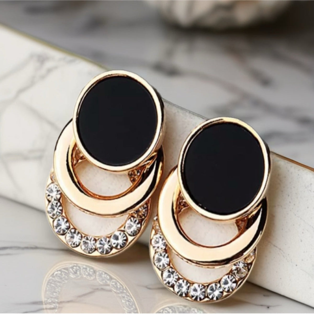 Zwart -gouden statementoorbellen met gelaagde geometrische bogen. Earrings by Tina