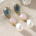 Blauw-roze hangende oorbellen met goudkleurige rand en parelachtige hanger. Earrings by Tina