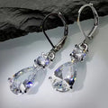 Zilverkleurige hangende oorbellen met grote transparante druppelsteentjes.Earrings by Tina