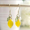 Goudkleurige hangende oorbellen met gele citroenen druppelhanger en bloemdetail. Earrings by Tina