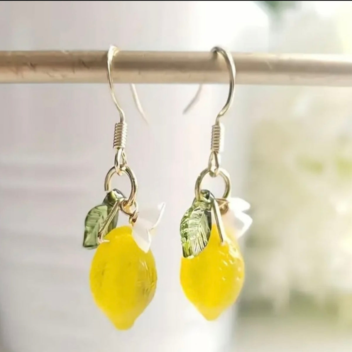 Goudkleurige hangende oorbellen met gele citroenen druppelhanger en bloemdetail. Earrings by Tina