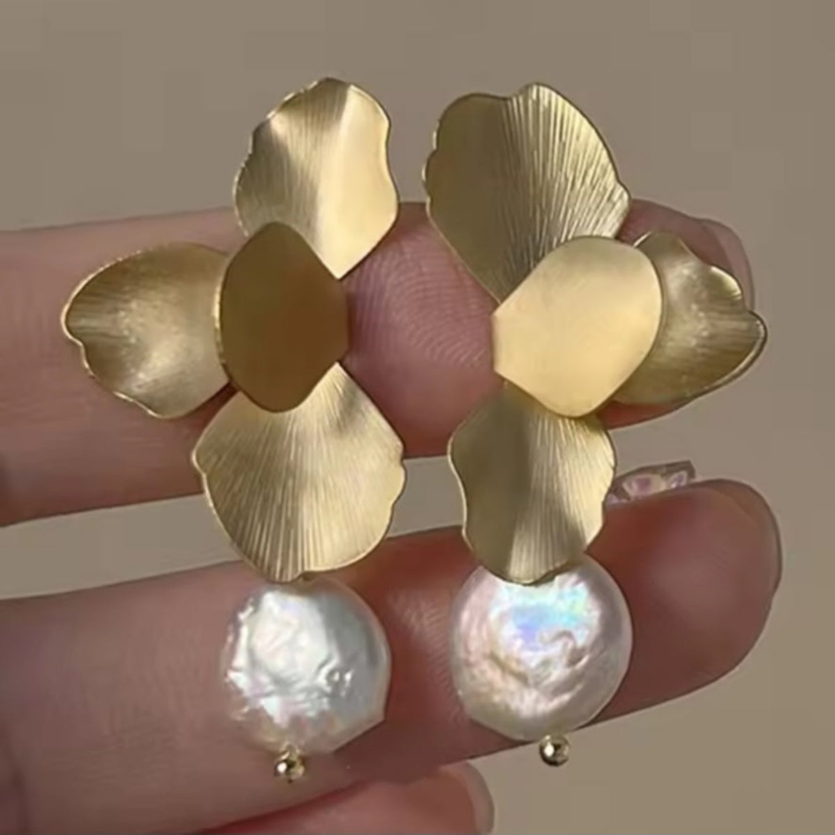 Grote goudkleurige bloemoorbellen met parelachtige platte parel. Earrings by Tina