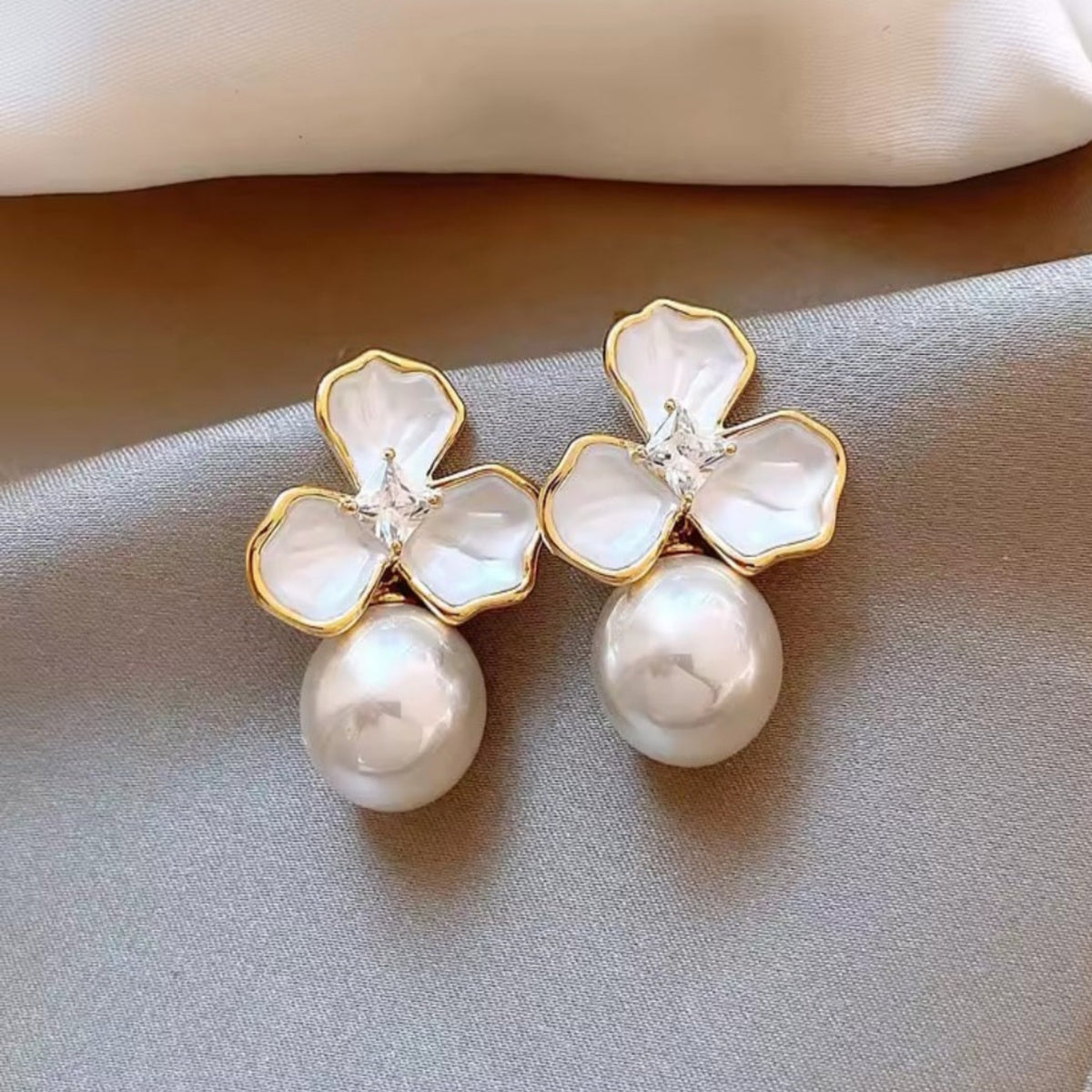 Parelmoerachtige bloemoorbellen met sierlijke parelhanger. Earrings by Tina