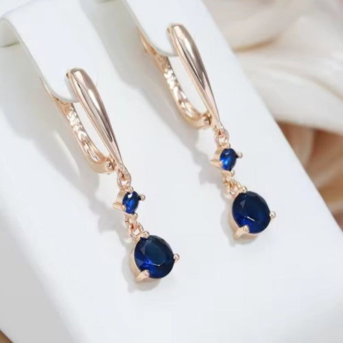 585 vergulde hangende oorbellen met donkerblauwe fonkelende steentjes. Earrings by Tina