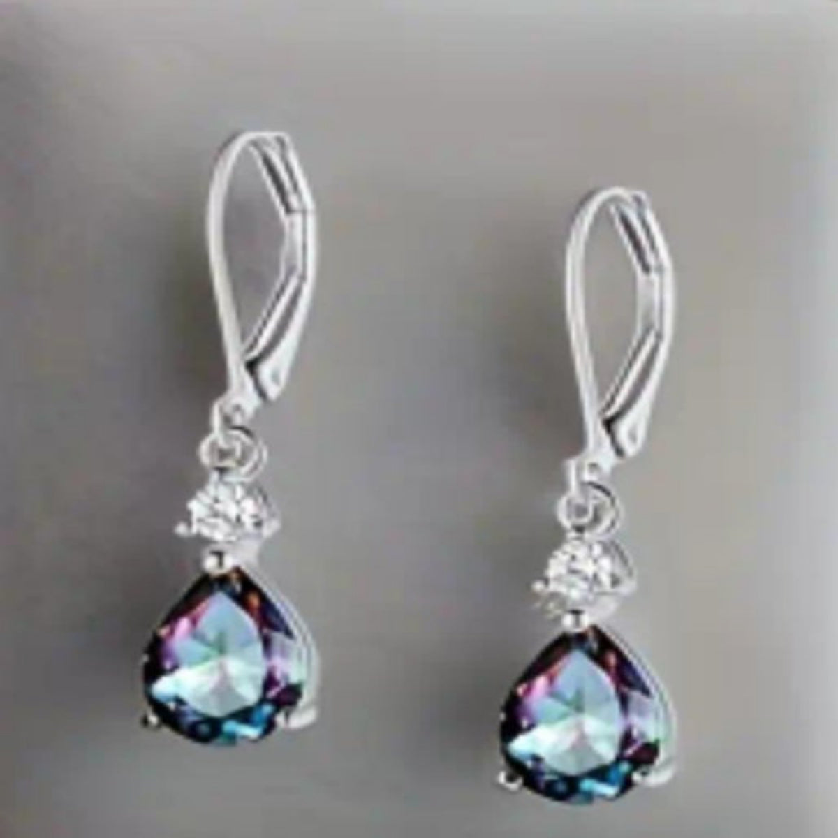 Zilverkleurige hangende oorbellen met paarse gefacetteerde steentje. Earrings by Tina